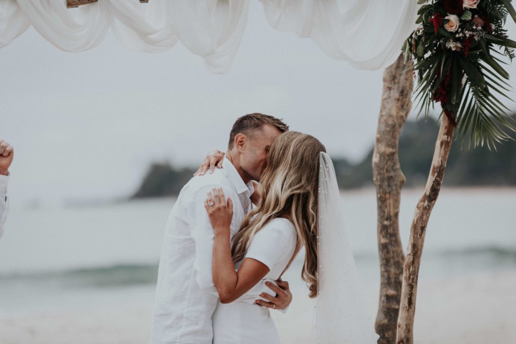 Jasmine and Ben sealing their vows with a kiss on the beach at Byron Bay.